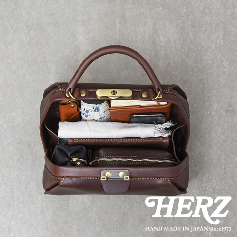 深棕色皮革手提包，內部裝有筆記本、錢包、手機、小包和一條毛巾。