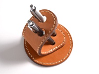 職人手作皮革兩用筆架，採用天然皮革製作，呈現溫潤的棕色調。筆架設計簡約，可容納兩支筆，附有精緻的縫線裝飾。