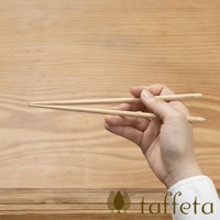 一雙21公分長的楓木圓筷，由人手持握，筷子呈自然淺木色，表面光滑，帶有細緻的木紋。