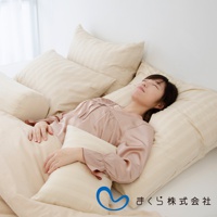 一位女子躺在多個淺米色條紋枕頭上，包括一個圓柱形枕頭。