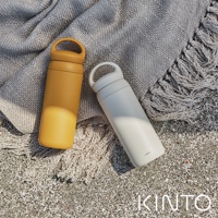 黃色和米白色DAY OFF提式輕巧保溫瓶，瓶身材質為不鏽鋼，帶有簡潔的提環設計，置於沙灘上的紋理毯子上。