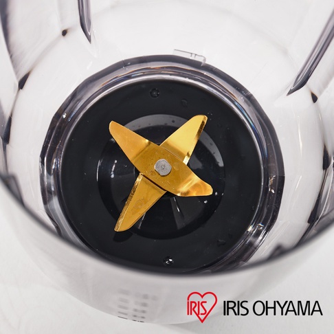 果汁機/料理機的透明塑膠攪拌杯內，特寫金色金屬刀刃組。