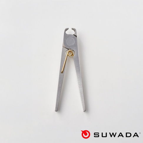 背景為白色的 SUWADA 諏訪田製作所 Petite 波堤指甲剪，金屬材質的指甲剪呈現簡約的細長造型，中央配有黃銅色的金屬彈簧裝置，右下角附有品牌標誌。