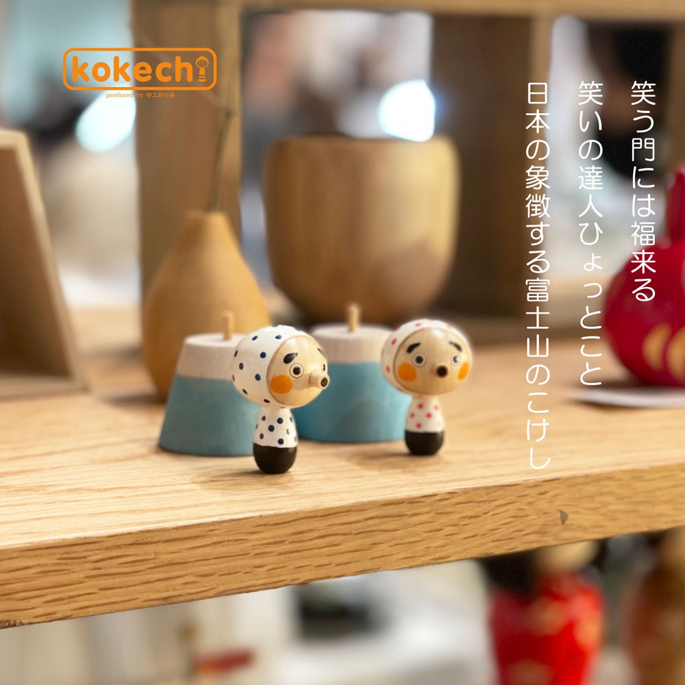 木芥子娃娃組合，包含兩個木製娃娃，一個白色頭巾點綴黑色圓點，另一個頭巾點綴紅色圓點，娃娃臉部為木質原色，帶有圓形紅臉頰和鉤狀鼻子。