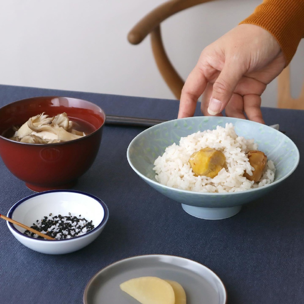 青色帶有綠色葉子圖案的平茶碗，盛有白米飯和兩塊栗子，旁邊是深紅色帶有圓形圖案的湯碗，碗內裝有切片香菇。