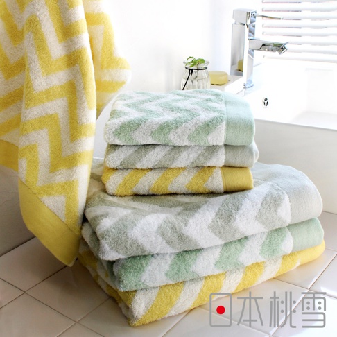 一疊今治毛巾，呈現綠色、黃色和白色交錯的鋸齒圖案，材質為柔軟的棉質。