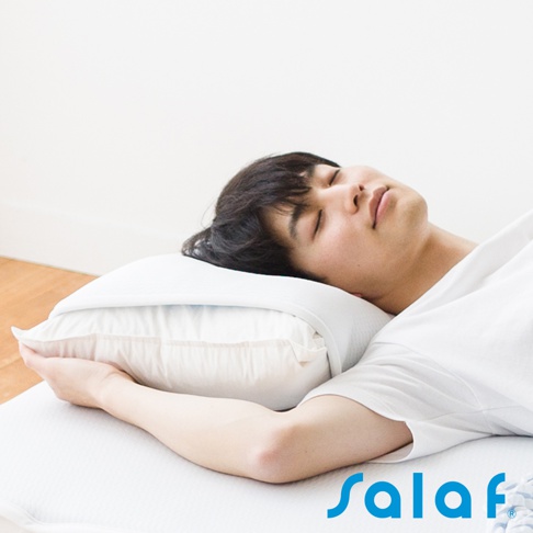 一名男性側臥在白色床墊上，頭枕著一個白色枕頭，枕頭套著一件白色枕套，材質看起來光滑透氣。