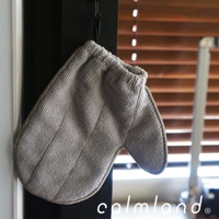 一隻淺灰色超細纖維除塵清潔手套，手套材質柔軟，表面有細緻紋理，掛在黑色掛鉤上，背景為木質百葉窗。