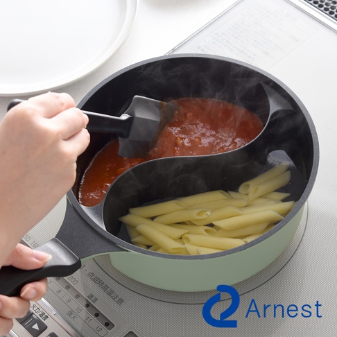 Arnest 鴛鴦料理鍋，一半煮番茄醬，另一半煮義大利麵，鍋具呈現淺綠色，灶台有日文說明。