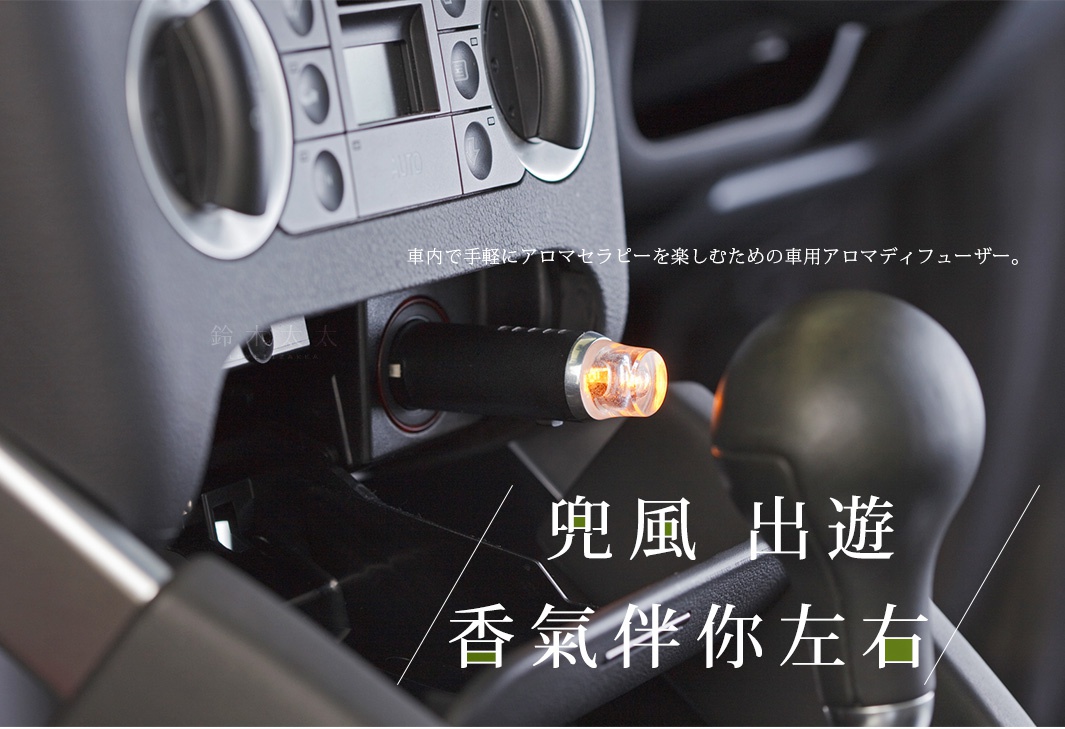 黑色的皮革車載擴香器，插入汽車點菸孔，頂端有橙色燈光，旁邊是汽車排檔桿。