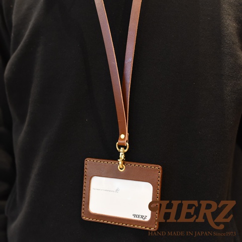 棕色皮革證件識別夾專用掛繩，搭配金色掛鉤，皮革夾正面有品牌標誌和文字，掛繩與夾子之間以金色金屬環連接。