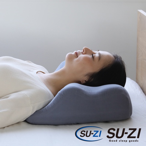 一名女子側臥在灰色記憶棉止鼾枕上，枕頭具有符合人體工學的曲線設計，支撐頸部和頭部。