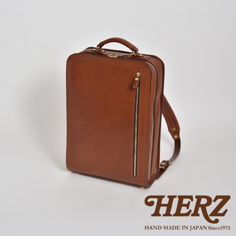 職人手作皮革商務電腦後背包 R-25，採用棕色皮革製成，配有金色拉鍊和金屬配件，設計簡潔大方，適合商務人士使用。