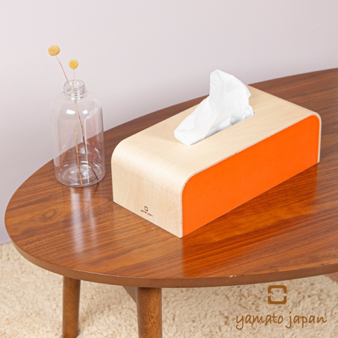 手作布藝木質面紙盒，淺木色木質外殼搭配明亮橘色布藝側邊，簡潔的弧形設計，盒內裝有白色面紙。