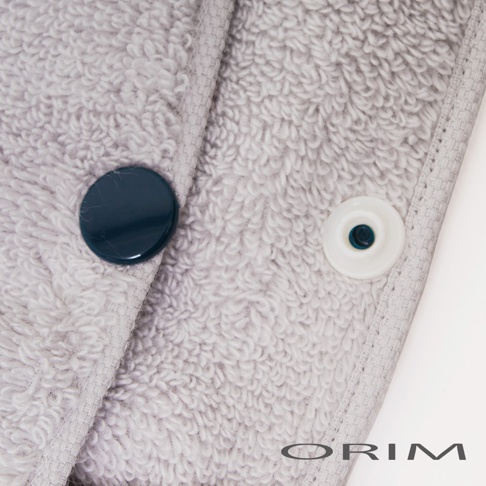 淺灰色毛巾材質的吹髮頭巾，設有深藍色圓形鈕扣和白色塑膠按扣。