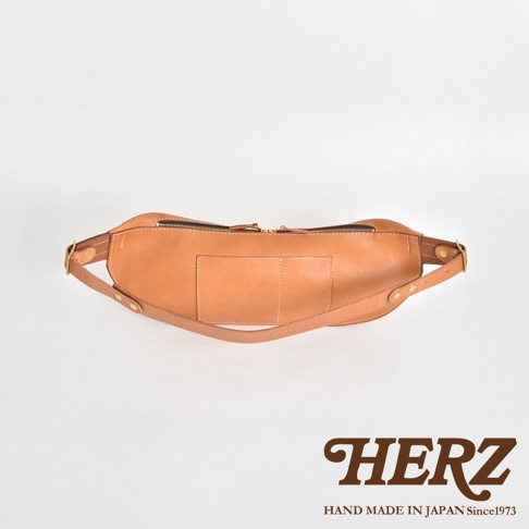 HERZ 職人手作皮革大容量斜背包，淺棕色，側邊視角，可作為腰包使用，下方有品牌標誌。