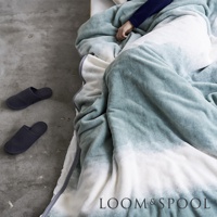 抗菌短絨舒柔單人毯，採用漸層藍綠色與白色設計，材質柔軟，搭配一雙深藍色拖鞋。