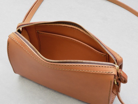棕色皮革製成的拉鍊單肩包，內部有兩個隔層，外部有精緻縫線裝飾。