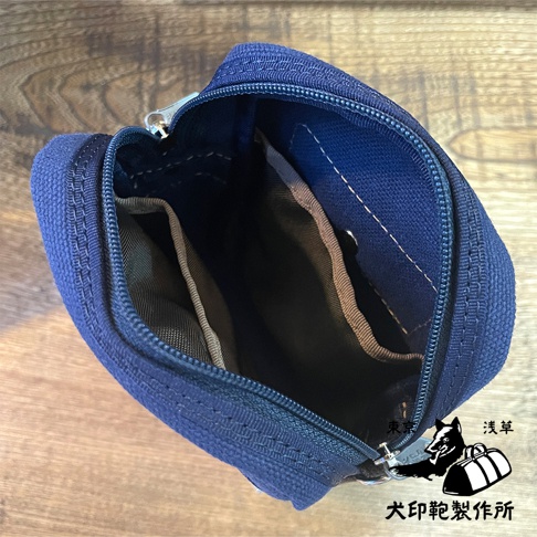 石洗帆布斜背手機包，深藍色，拉鍊開合，內部有分隔層，材質為帆布。