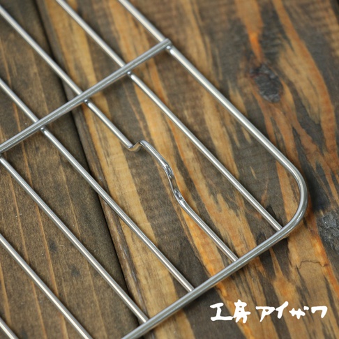 銀色方形不鏽鋼瀝油架，網格狀結構，邊緣圓潤，置於木紋桌面。