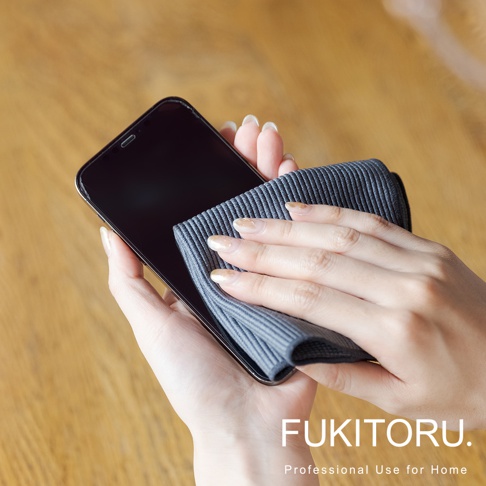 雙手持深灰色超細纖維清潔布擦拭黑色手機螢幕。