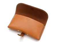 棕褐色皮革製成的眼鏡收納盒，翻蓋設計，帶有金屬扣帶。內裡為深棕色皮革，表面壓印有品牌標誌。