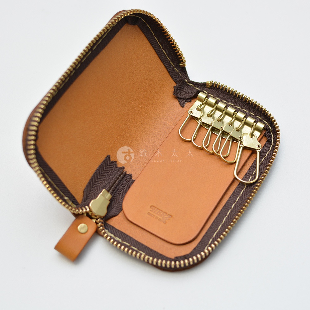 一個棕色皮革鑰匙包，打開拉鍊，露出內部和六個金屬掛鉤。