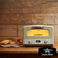 淺綠色復古多用途烤箱，配有銀色把手和兩個旋鈕，烤箱內有正在烘烤的吐司。旁邊擺放著幾片烤好的吐司，置於木製砧板上。