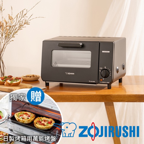 黑色象印電烤箱，設有玻璃門、黑色把手、定時旋鈕和品牌標誌。烤箱放在木桌上，背景為米色窗簾和裝飾植物。