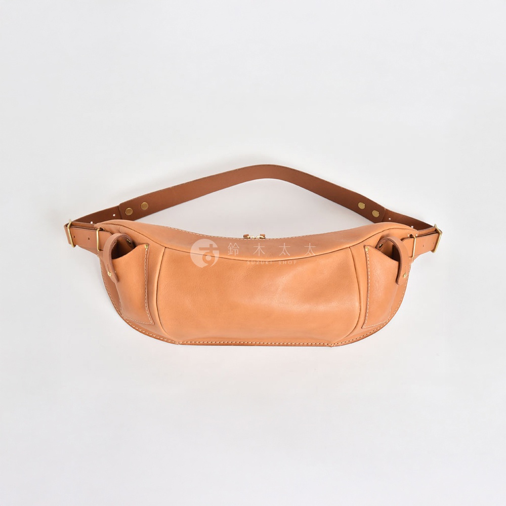 一個淺棕色的皮革斜背包，中間有拉鍊開口，兩側各有一個小口袋，背包帶為棕色皮革。