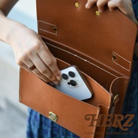 職人手作的棕色皮革迷你單肩包，內部可放入手機。包款採用手工縫製，搭配金色金屬扣。