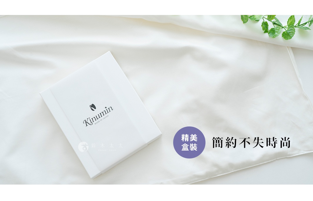 白色禮盒內含 Kinumin 棉絲混紡美髮枕套，枕套平鋪於白色絲綢布料上，一側有綠葉裝飾，營造出簡潔優雅的視覺效果。