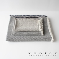 三條堆疊的浴巾，表面有斜紋編織紋理，邊緣有流蘇設計。兩條為灰色與淺灰色交織，一條為淺灰色。