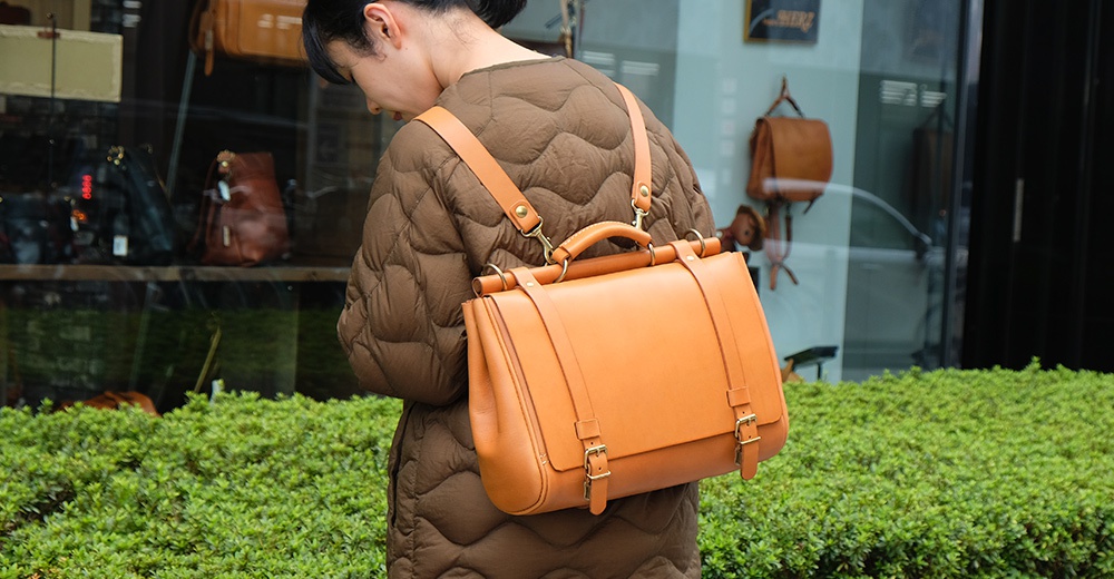 日本HERZ職人手作皮革屋瓦風側背包，採用棕色菱格紋鋪棉外套搭配橘色皮革背包，展現文青復古風格。