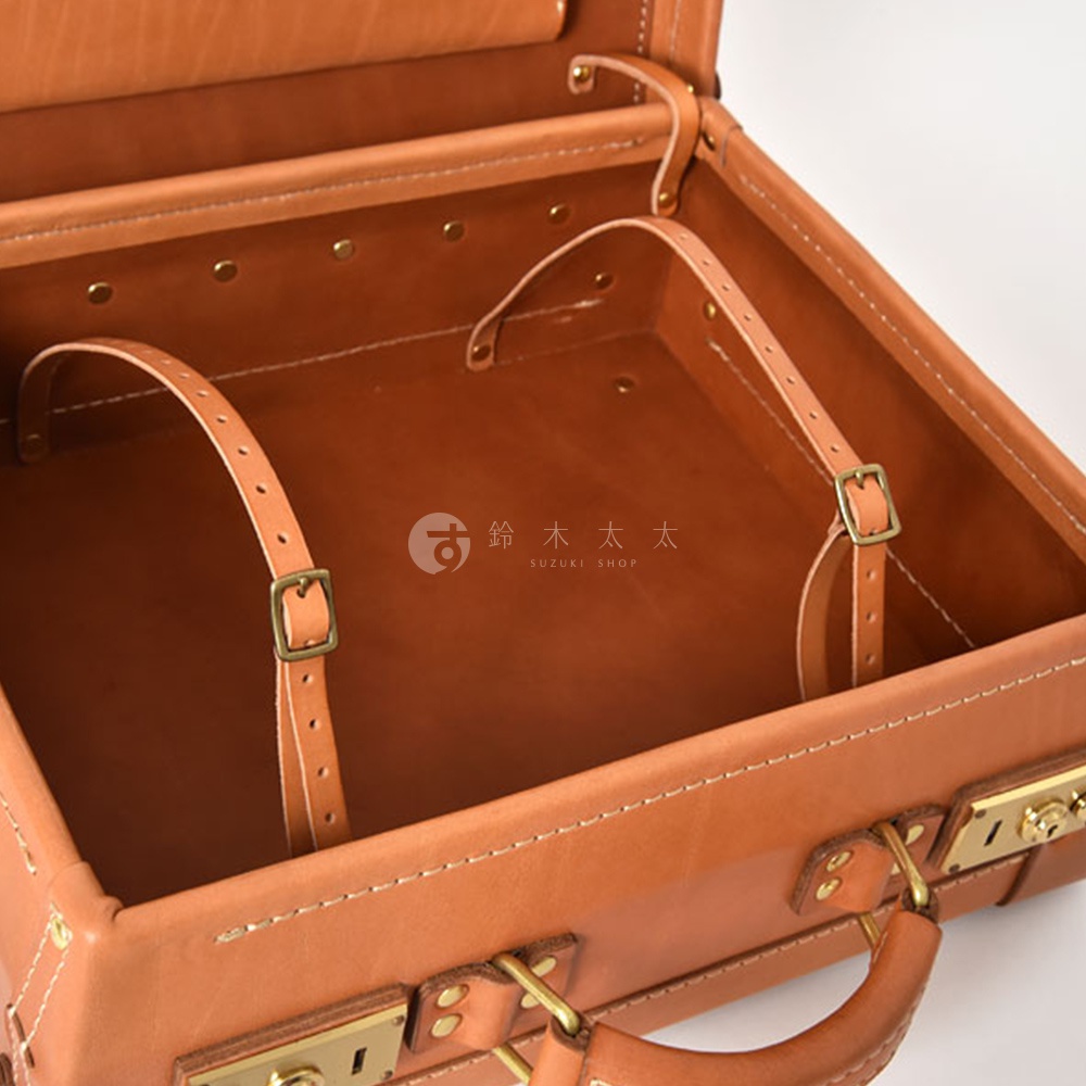 職人手作皮革英倫風便攜手提行李箱，展示內部結構。箱體為淺棕色皮革，內部有兩條可調節的皮革束帶，束帶末端設有黃銅色金屬扣。箱內邊緣及接縫處有明顯的白色縫線。