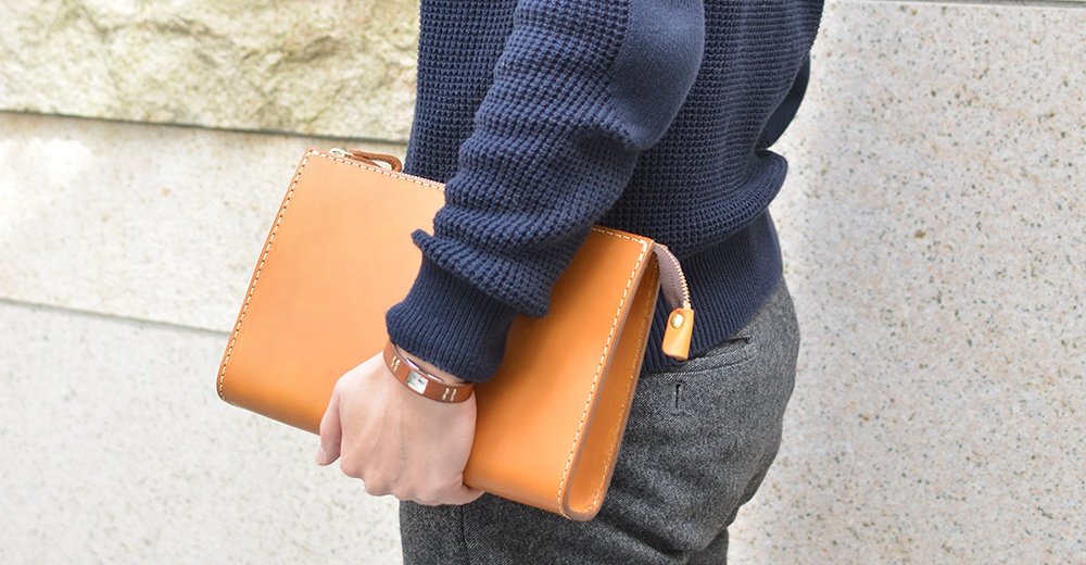 職人手作皮革三角底拉鍊手拿包，暖棕色皮革，簡約設計，搭配同色系皮革拉鍊頭，質感細緻。