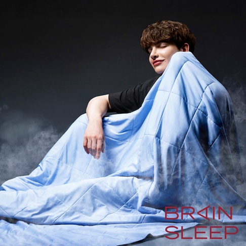 一位男子被淺藍色菱形格紋涼感被包裹，被子質地輕柔，營造出舒適涼爽的氛圍。