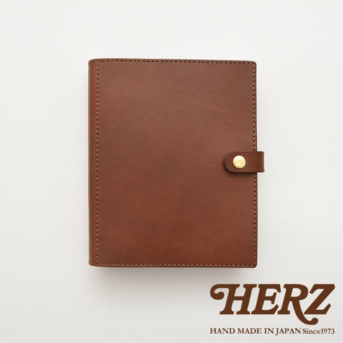 職人手作皮革A5手帳/記事本書套，採用光滑棕色皮革製成，邊緣有精細縫線，並以金色金屬釦環固定。