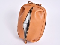 淺棕色皮革製成的立體斜背包，拉鍊部分敞開，露出內部淺灰色毛巾狀物品，搭配金色拉鍊和皮革拉環，縫線明顯。