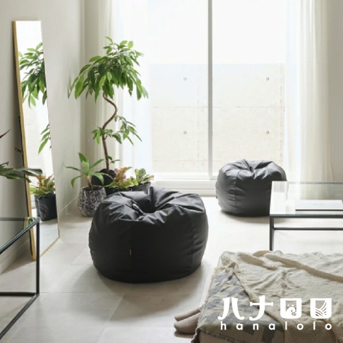 兩個黑色皮革懶骨頭沙發，擺放在客廳中，旁邊有綠植、鏡子和茶几。