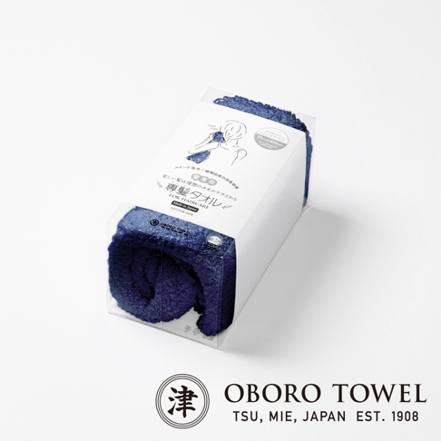 深藍色毛絨質地的專髮擦髮巾，包裝在透明塑膠盒內，盒上有日文說明與人像圖示，下方有「OBORO TOWEL」品牌標誌。