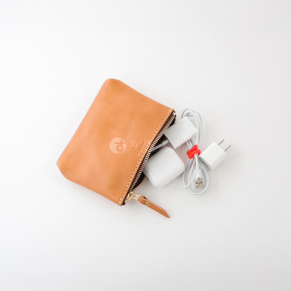 職人手作皮革長方形拉鍊收納包，淺棕色皮革，拉鍊為金色，內含白色耳機及充電器，整體簡潔實用。