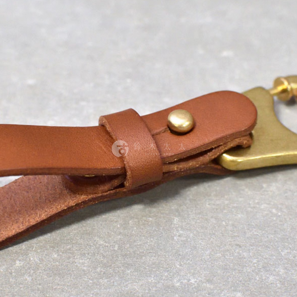 職人手作皮革鑰匙圈，採用棕色皮革製作，搭配黃銅金屬扣環與铆釘，設計簡約實用。