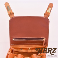 職人手作皮革復古風旅行後背包，展示棕色皮革材質、金屬釦環和拉鍊細節，以及抽繩開口設計。