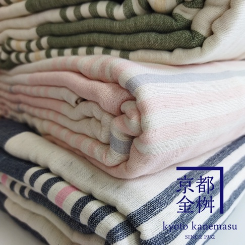 堆疊的六層紗條紋毛毯，有綠色、粉紅色和深藍色條紋，材質呈現細緻紋理