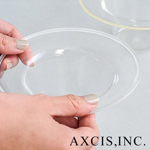 一隻手拿著一個透明玻璃製成的深型點心碗，碗的邊緣圓潤。另一個同款玻璃碗在背景中，碗口有淡黃色邊緣。