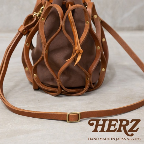 日本HERZ手工皮革編織水桶包，其獨特的皮編織網罩與棕色內袋形成對比，精緻的手工藝彰顯出品牌Since 1973的堅持。