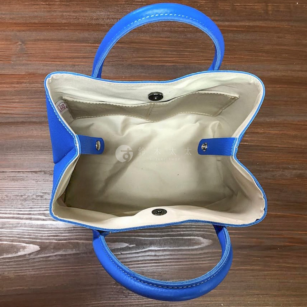 藍色帆布與皮革拼接手提托特包，內部有夾層與磁扣，雙提把設計，簡約實用。