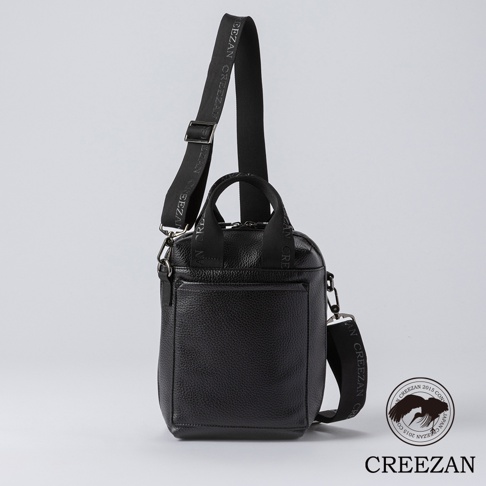 黑色荔枝紋皮革方形側背包，配有織帶提把與可調式肩帶，肩帶上印有品牌字樣。包款正面有拉鍊外袋。