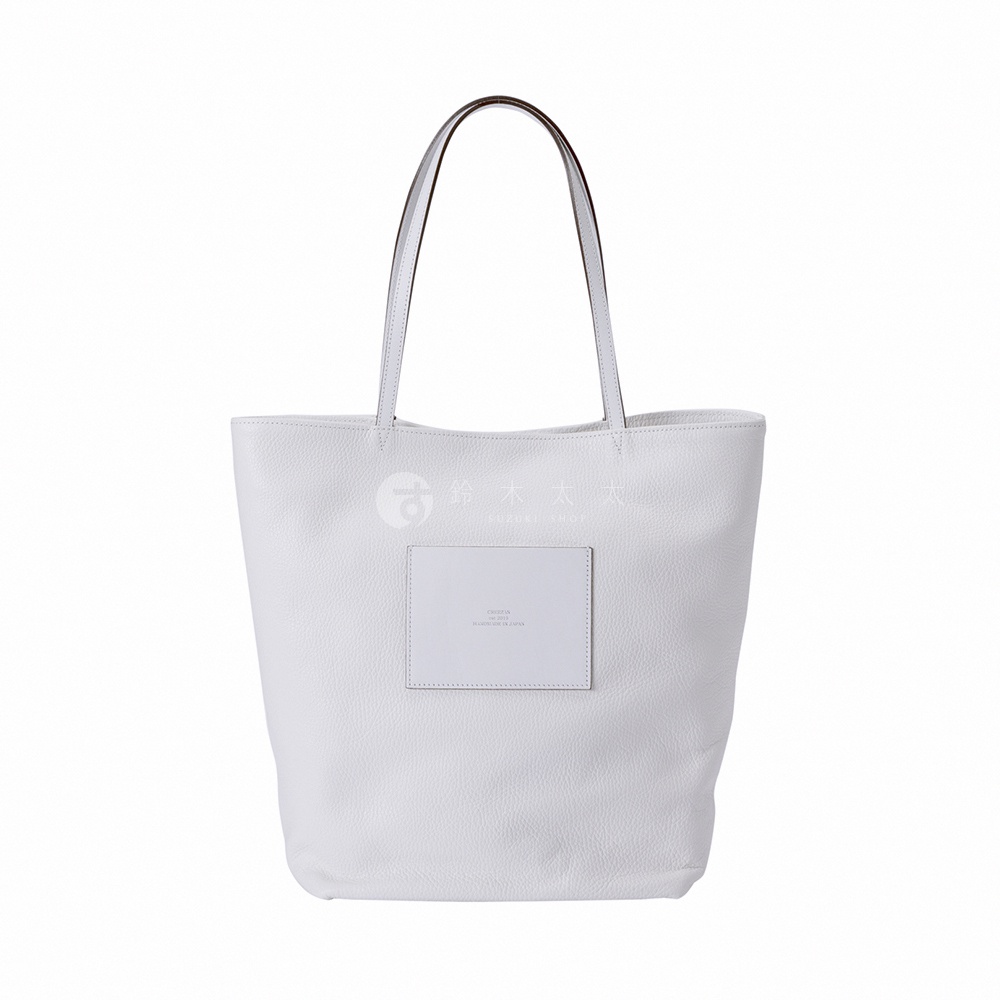 JETTER 大容量肩背托特包，採用柔軟的皮革材質，呈現柔和的淺灰色，包身中央有一個方形皮革標籤，標籤上印有品牌標誌和「MADE IN JAPAN」字樣。
